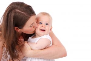 woman lovingly holding and kissing a baby