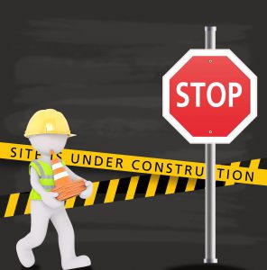 stop sign and a cartoon character of man carrying cones with a sign saying Site is under construction