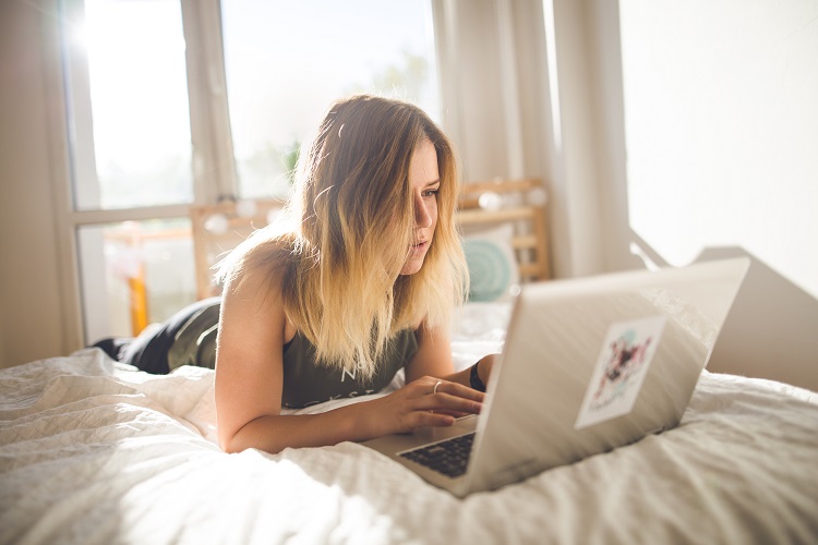 woman working on laptop in bed