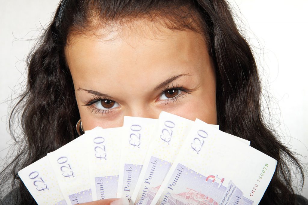 woman holding banknotes spread across her face